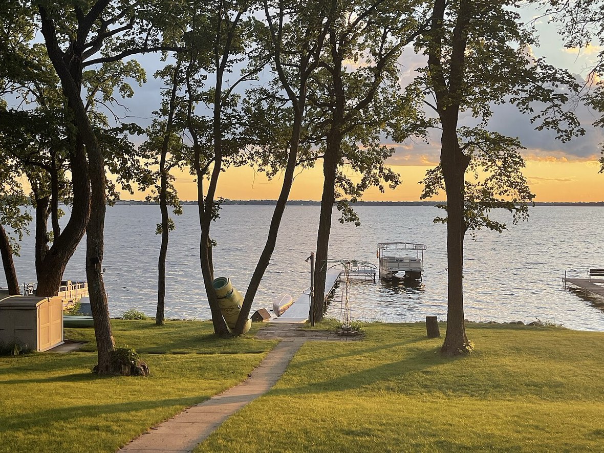A West Central Minnesota lake property at sunset with a dock and shoreline lawn