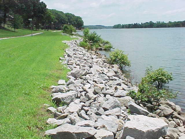 Riprap rock protecting a grassy lake shoreline